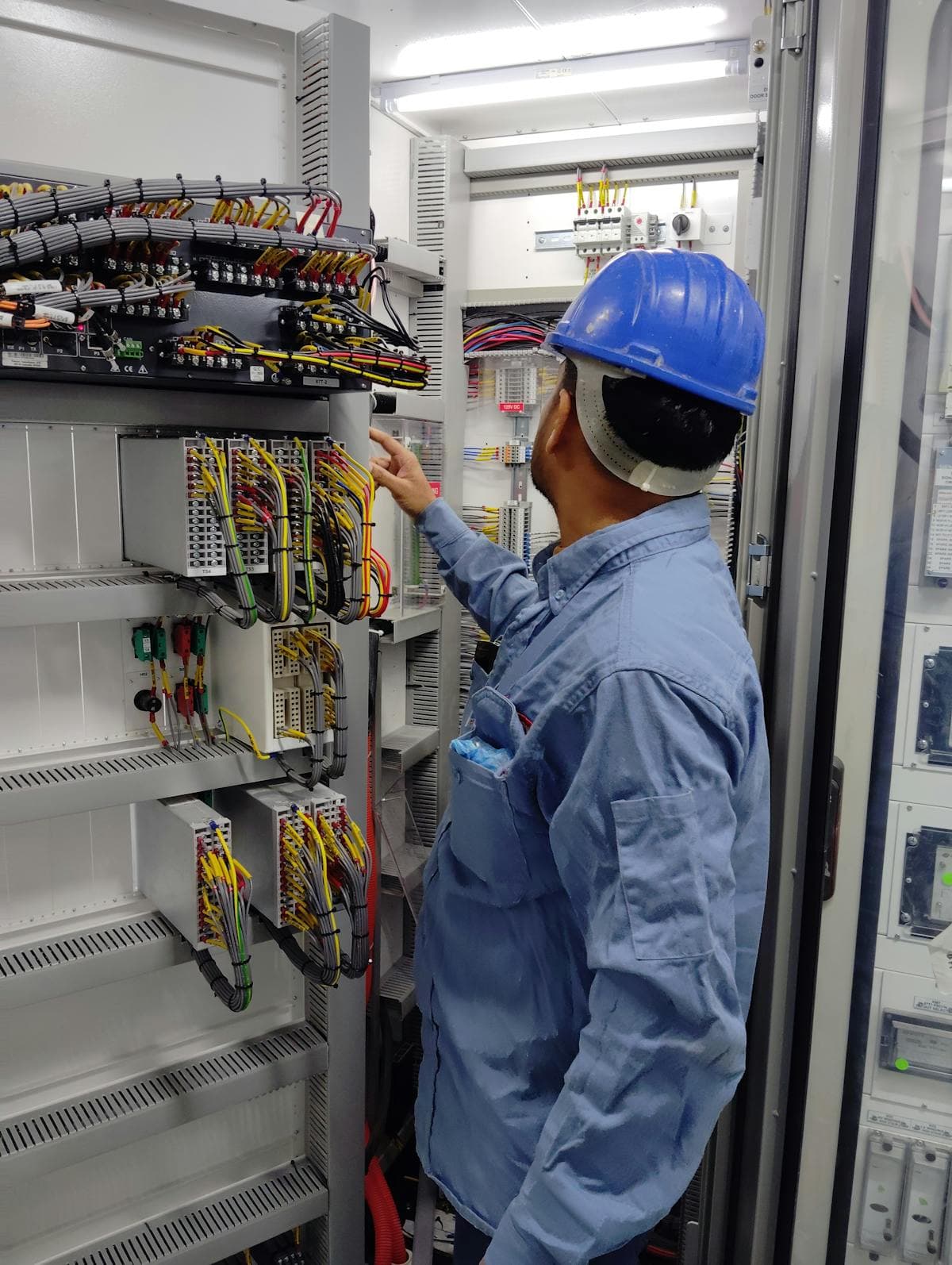 Elektriker mit Schutzhelm dokumentiert Installationsarbeiten vor Ort